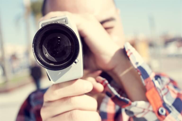 man looking through small camera lens